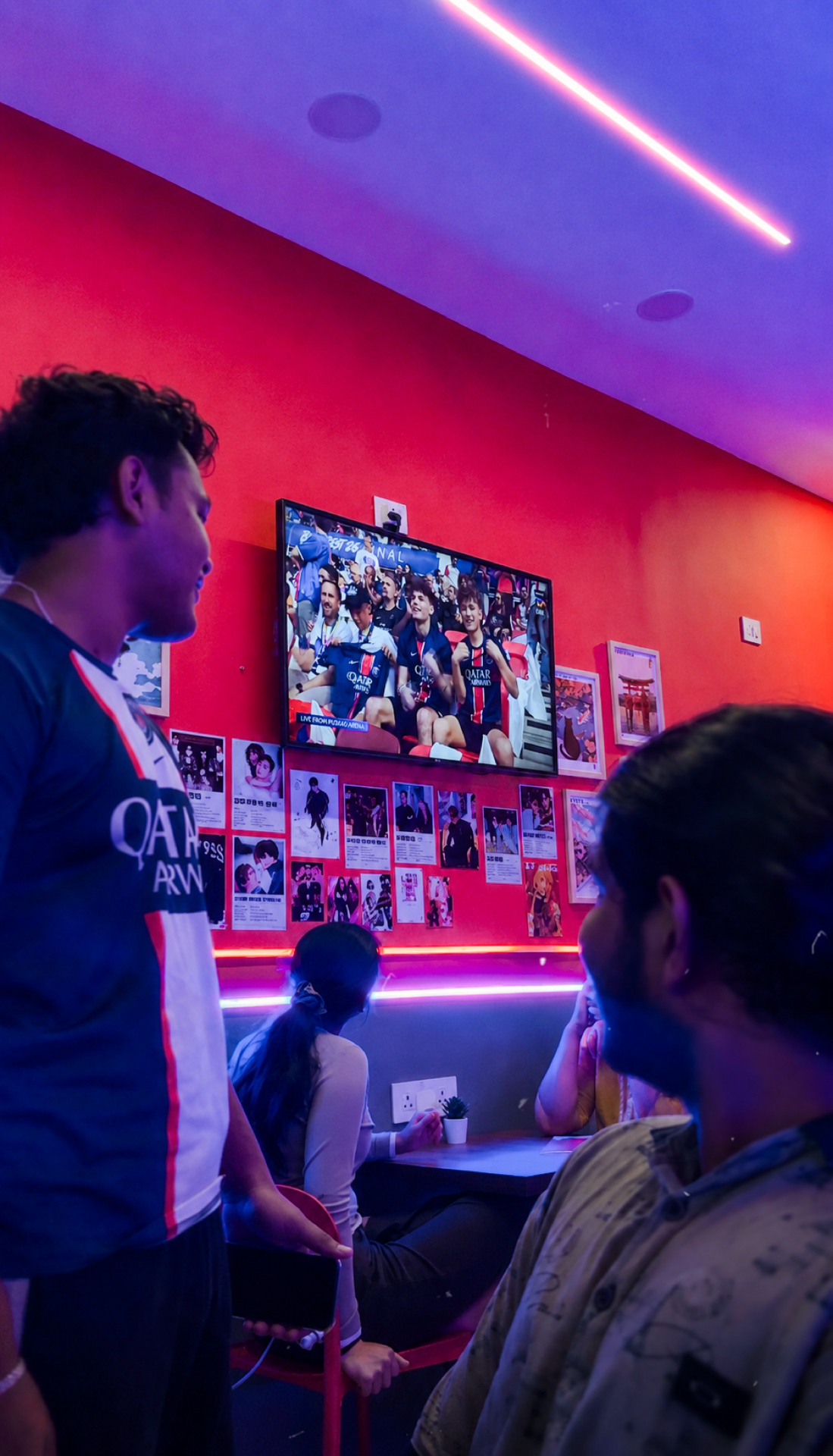 Neon-lit interior of K-Town Bites with friends watching TV